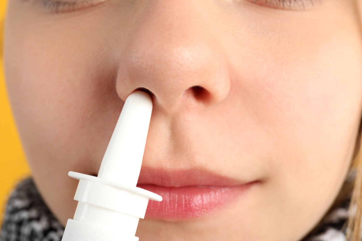 Young woman using nasal drops, close up